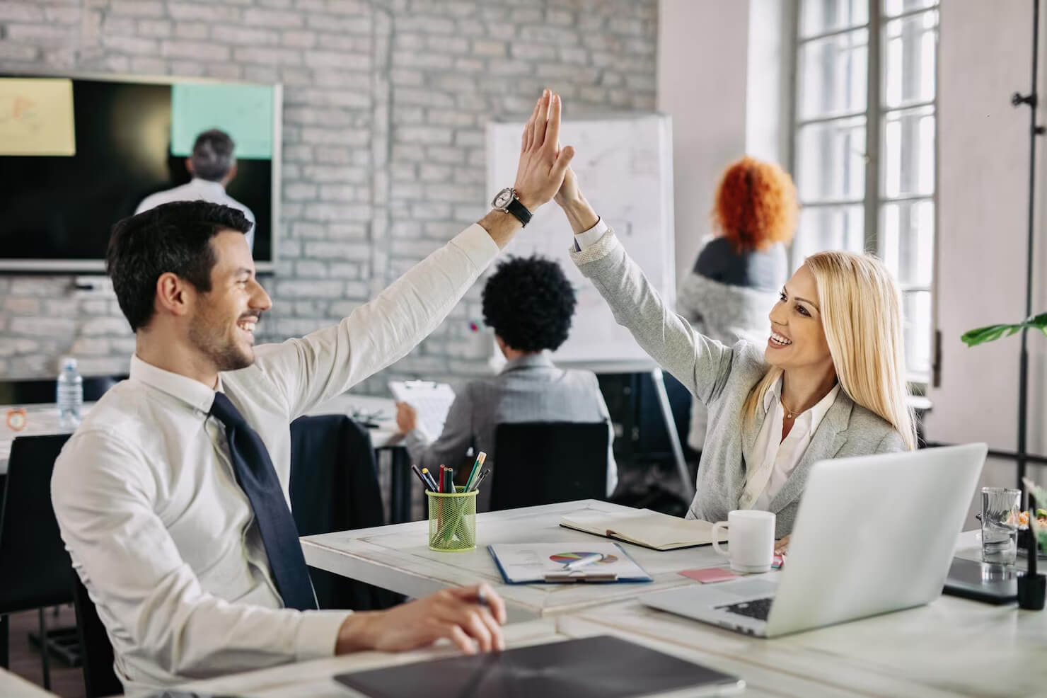 Happy business people supporting each other and giving high five in the office