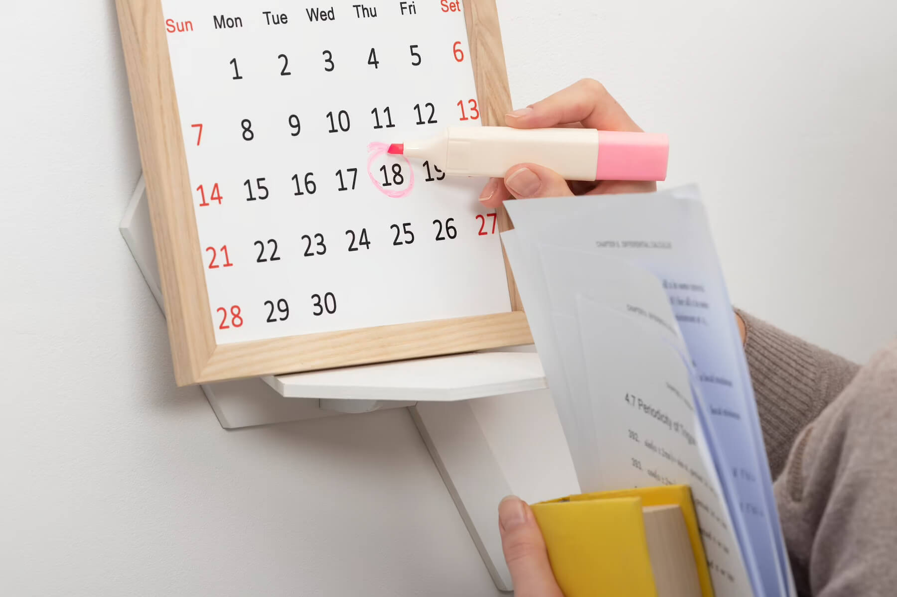 Marking a deadline on a calendar with a pink highlighter