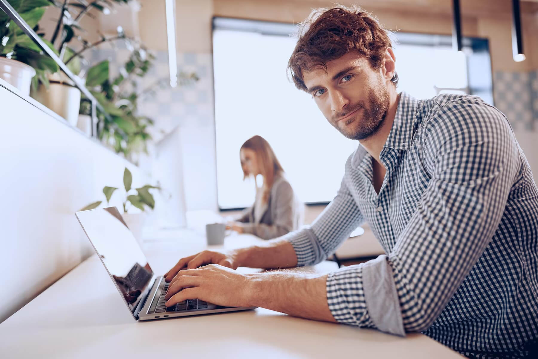Young bearded successful businessman working on laptop in office